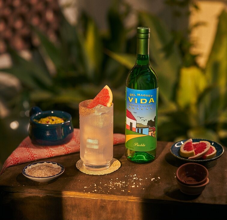 A Del Maguey Vida bottle beside a highball cocktail and grapefruit