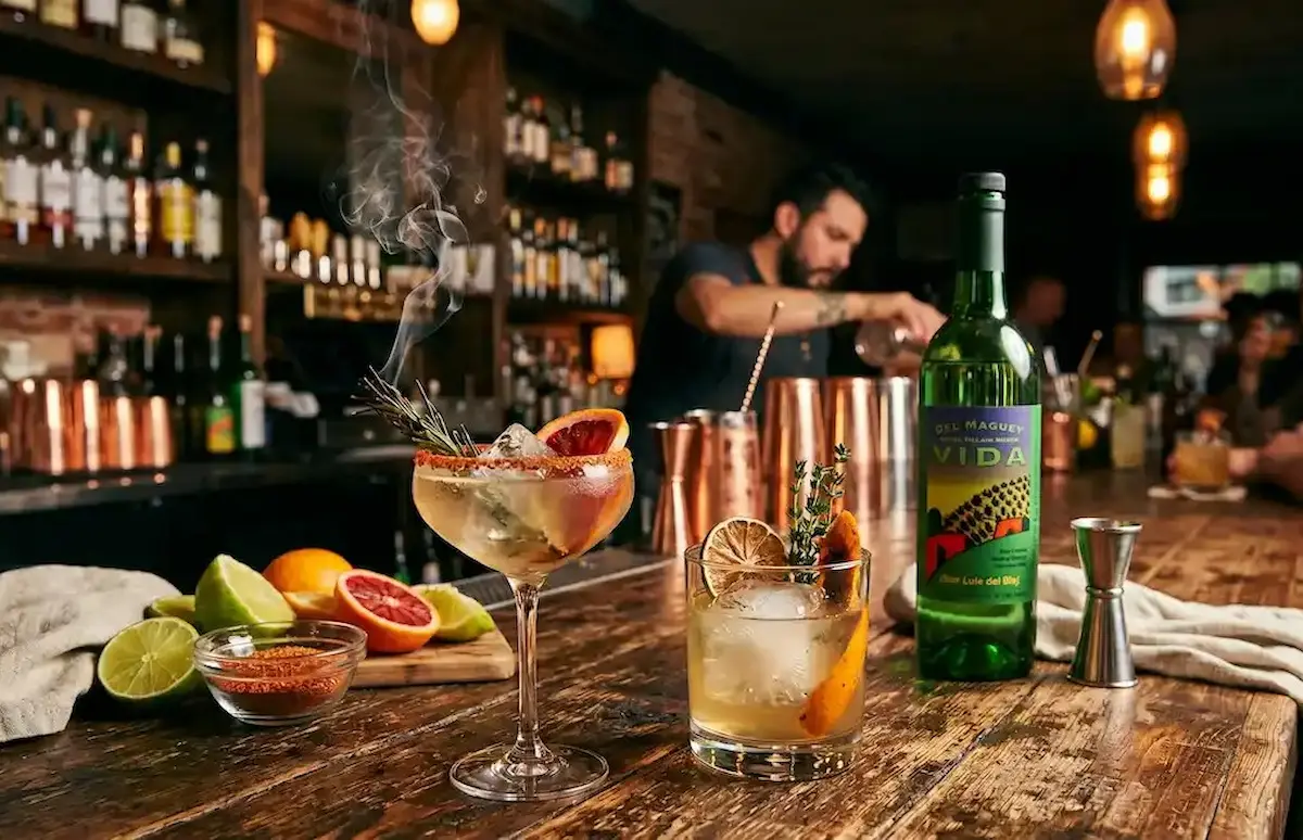 Smoky mezcal cocktails on a bar with Del Maguey Vida mezcal and citrus.