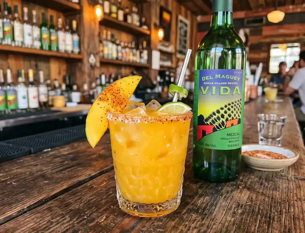 Mango Vida Rita mango mezcal margarita in a rocks glass over fresh ice with a skewered mango slice