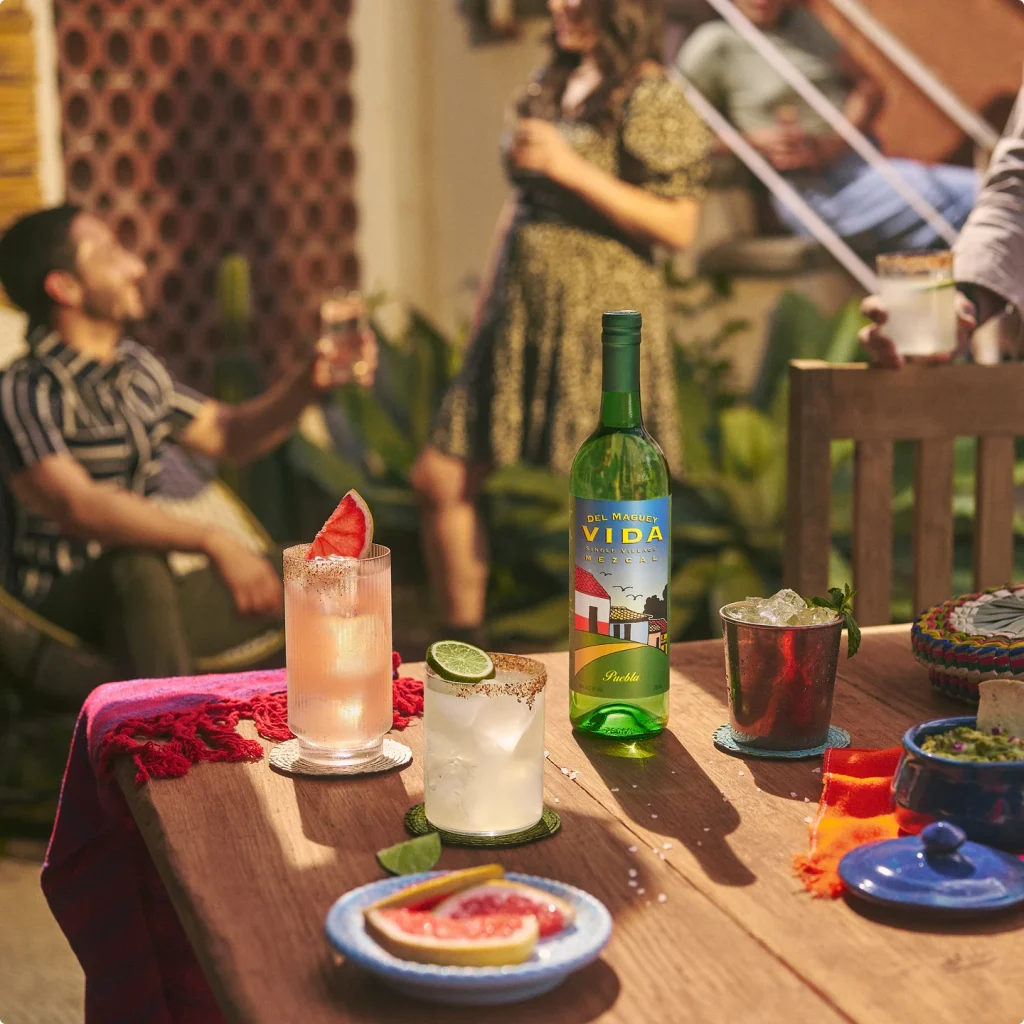 People gathered around a table with a bottle of Del Maguey Vida and cocktails